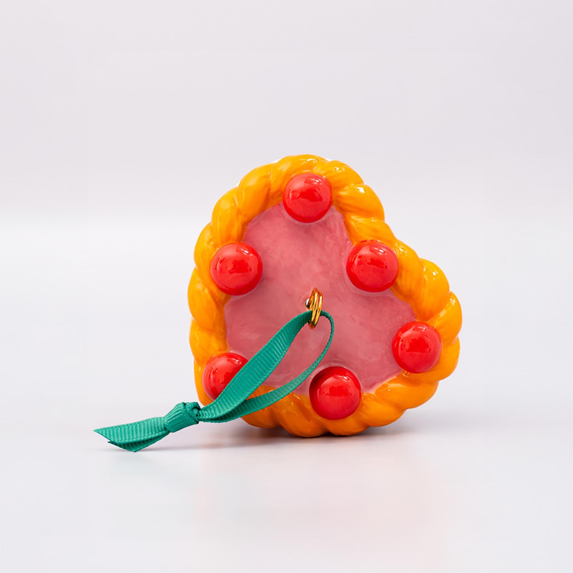 Top view of ornament cake with pink filling, orange and white striped sides, and red cherries on a white background