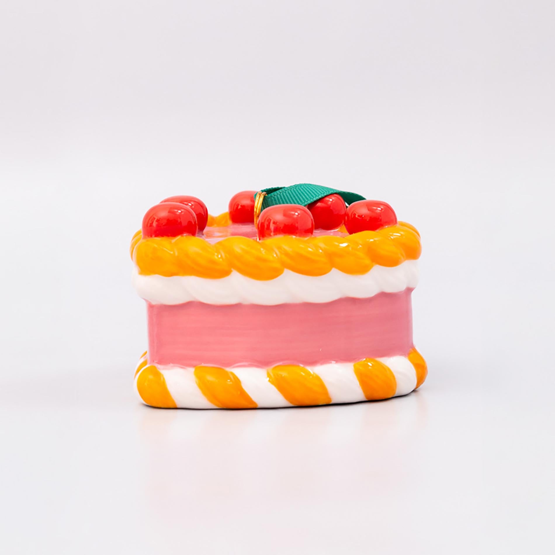 Ornament cake with pink filling, orange and white striped sides, and red cherries on a white background