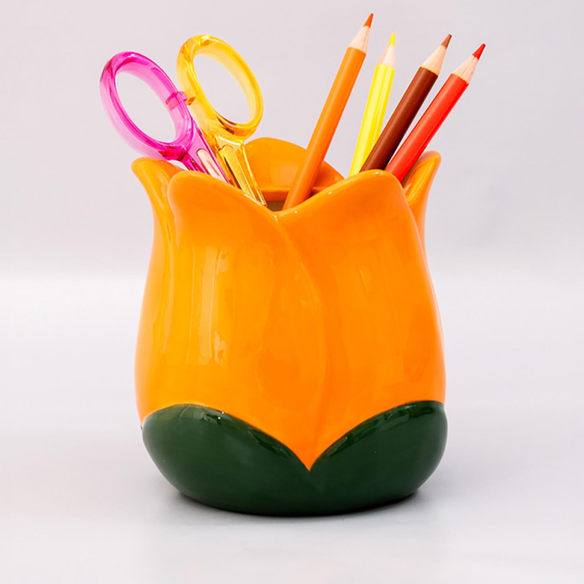 Orange tulip-shaped pen holder with colorful stationery items on a white background