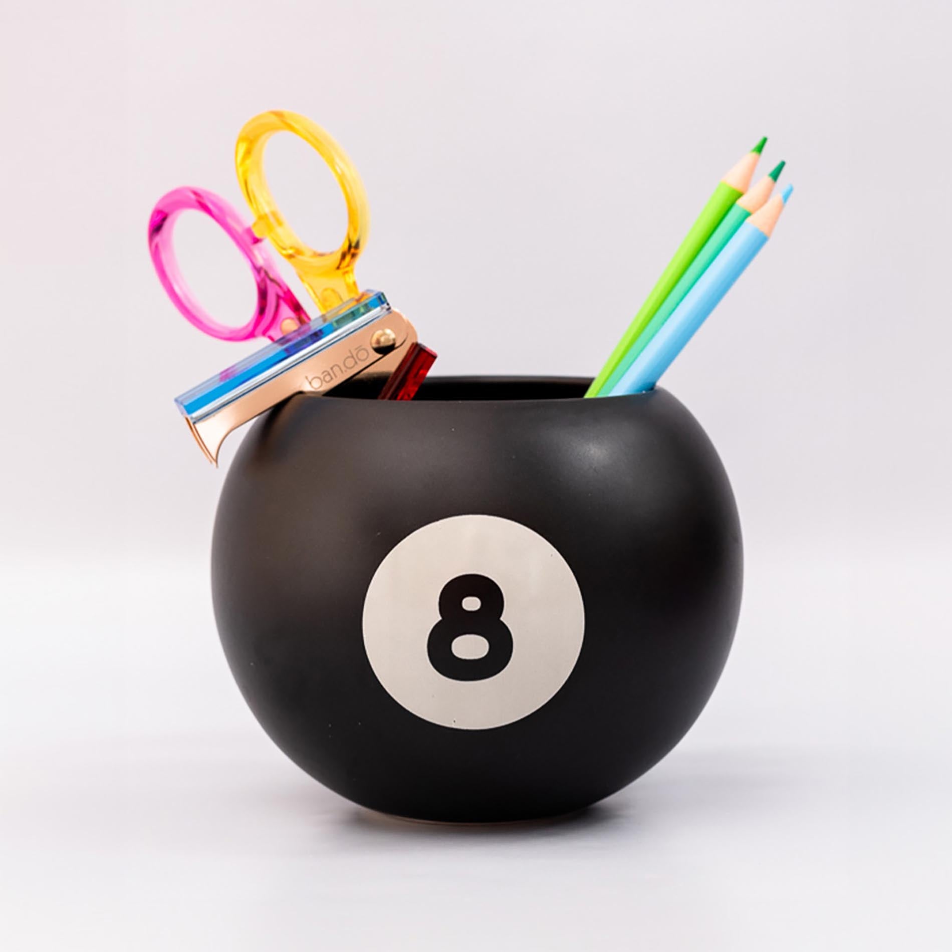 Black billiard ball-shaped holder with number 8 holding stationery items on a white background