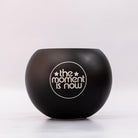Black bowl with 'the moment is now' text on a white background