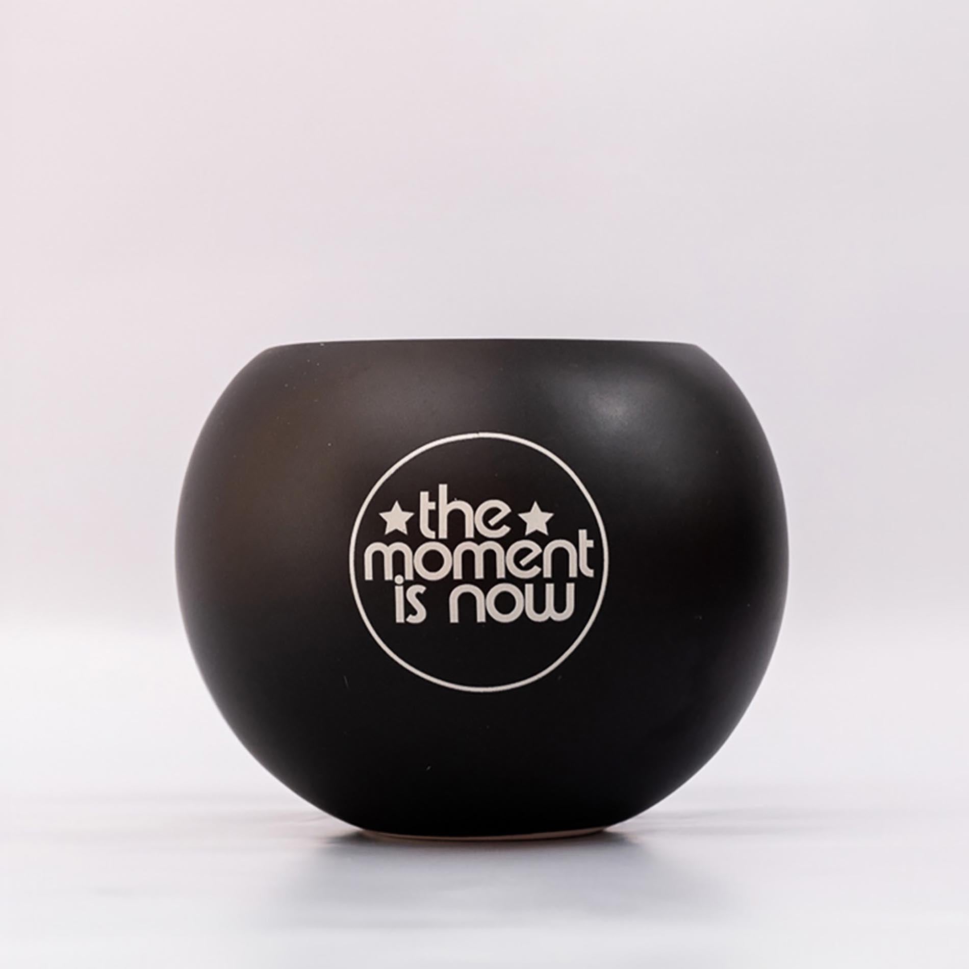 Black bowl with 'the moment is now' text on a white background