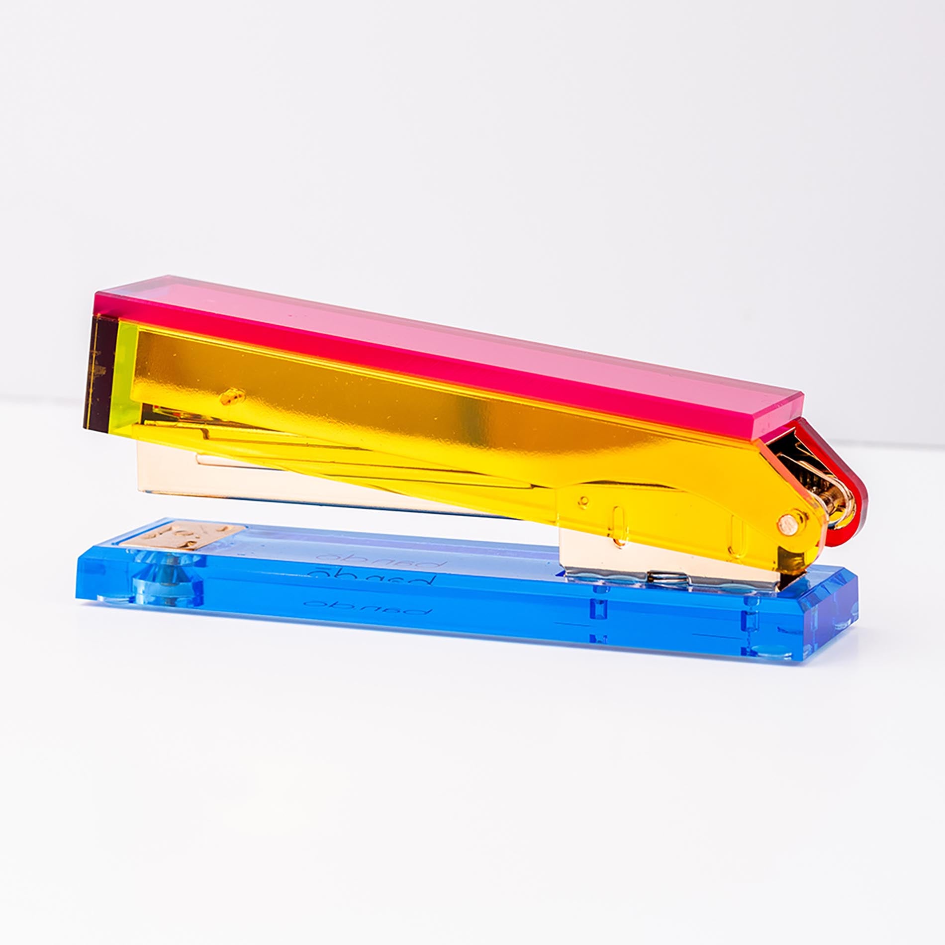 Colorful stapler with pink top, yellow middle, and blue base on a white background