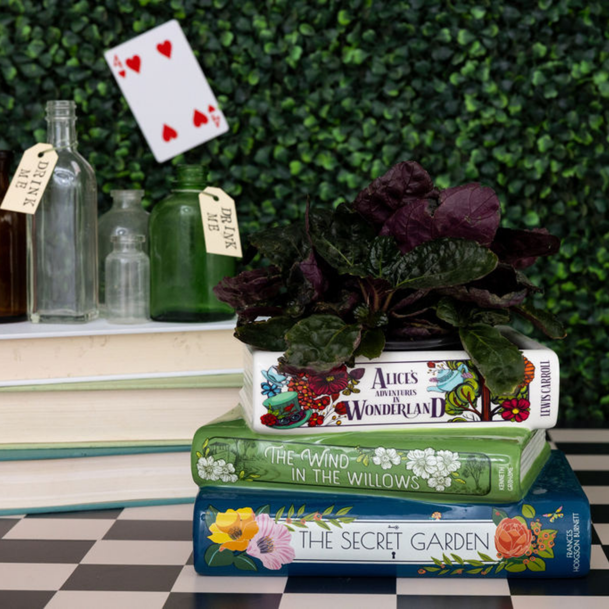 Stack of books with a plant on top, set against a green foliage background.