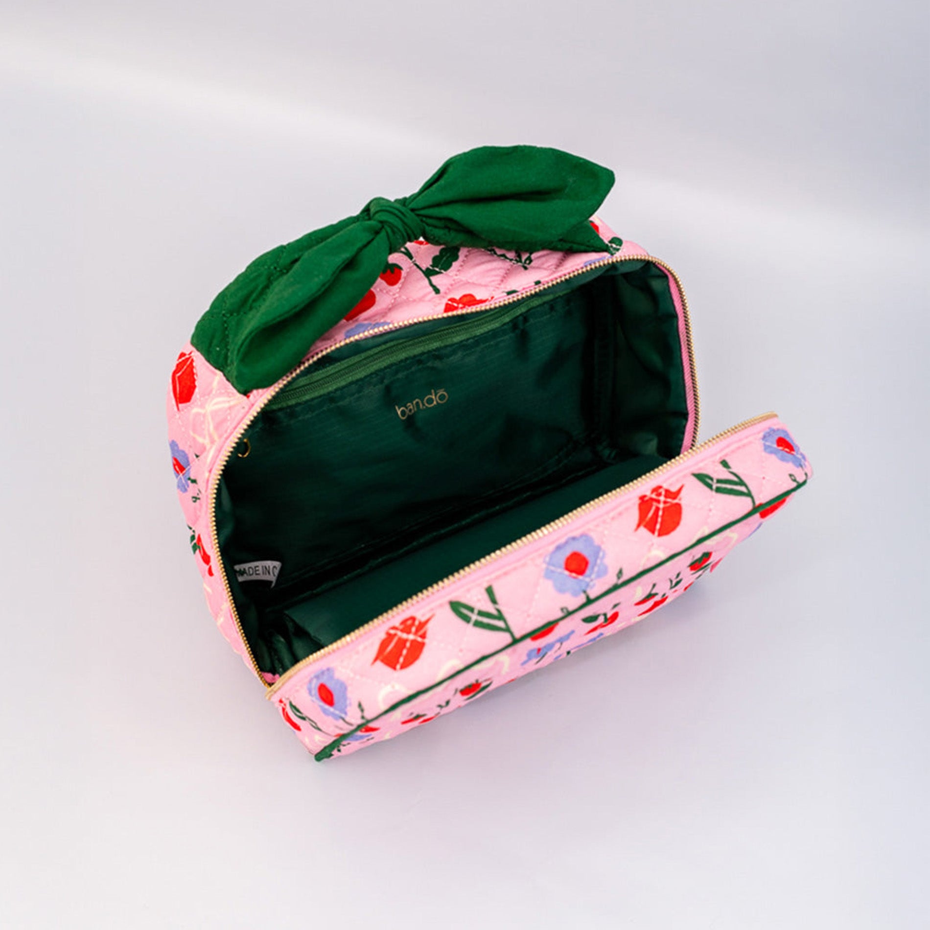 Floral-patterned pouch with a green bow on a light gray background