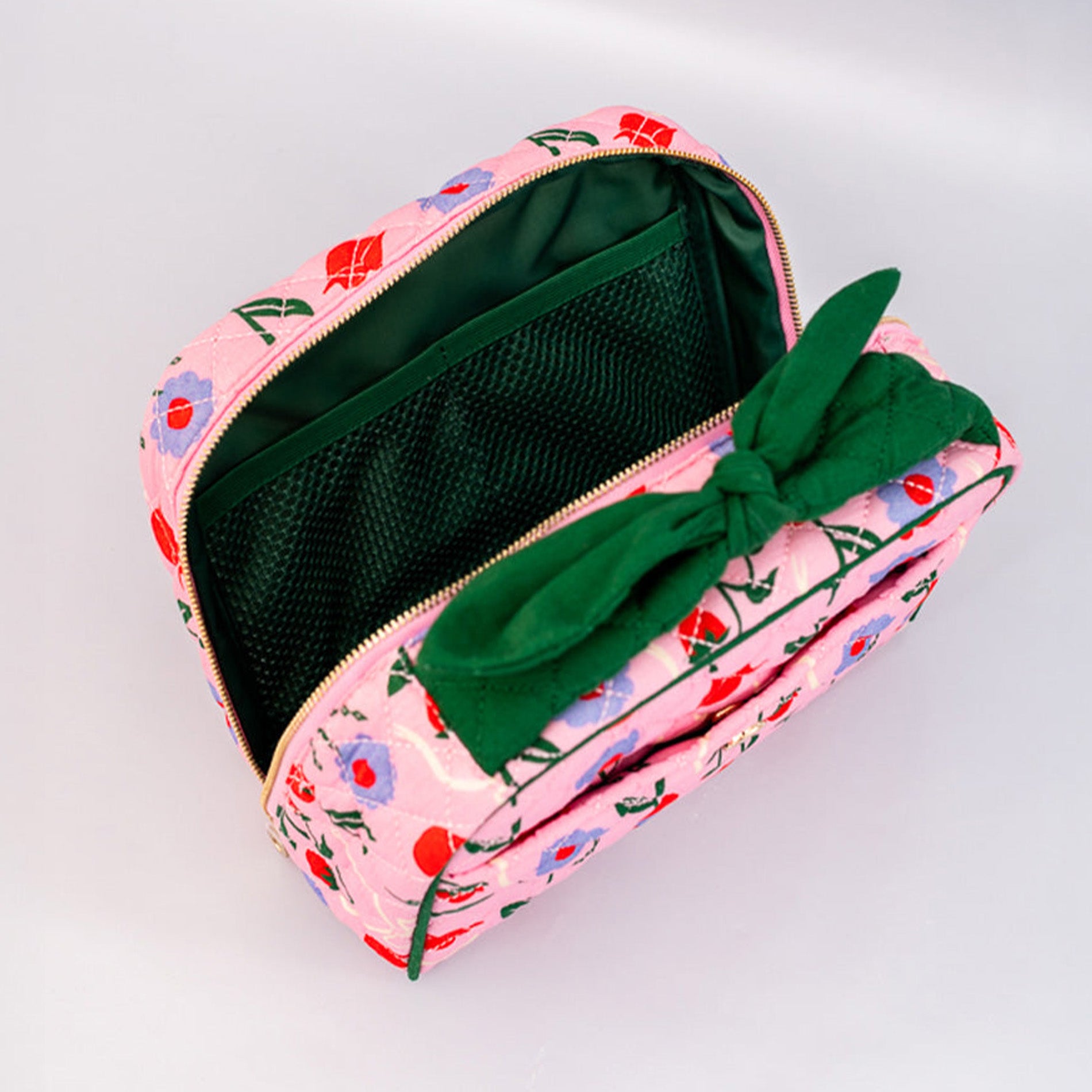 Pink floral-patterned pouch with a green bow on a light gray background