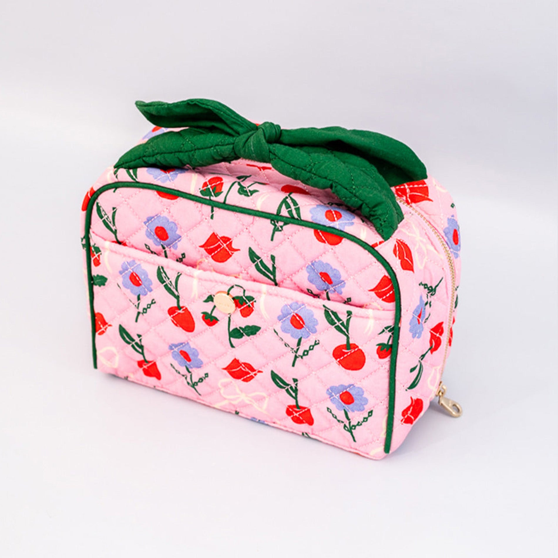 Pink floral-patterned bag with a green bow on a white background