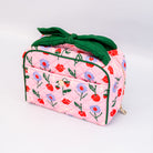 Pink floral-patterned bag with a green bow on a white background