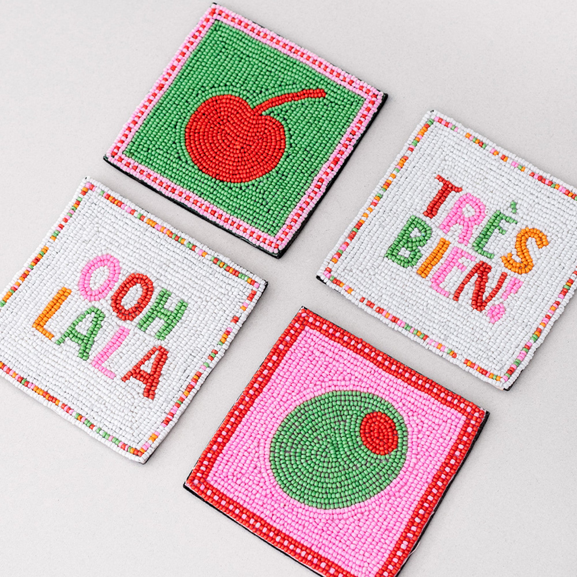 Four colorful coasters with text and designs on a light gray background