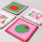 Colorful embroidered coasters with various designs on a light gray surface