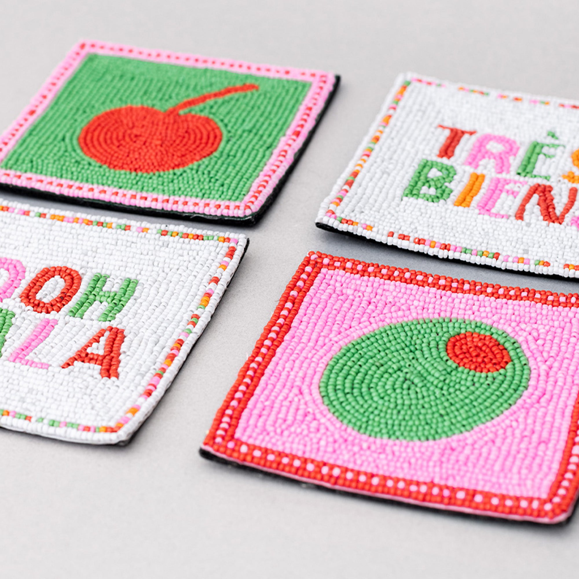 Four colorful coasters with text and designs on a gray background