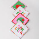 Four colorful coasters with text and designs on a light gray background