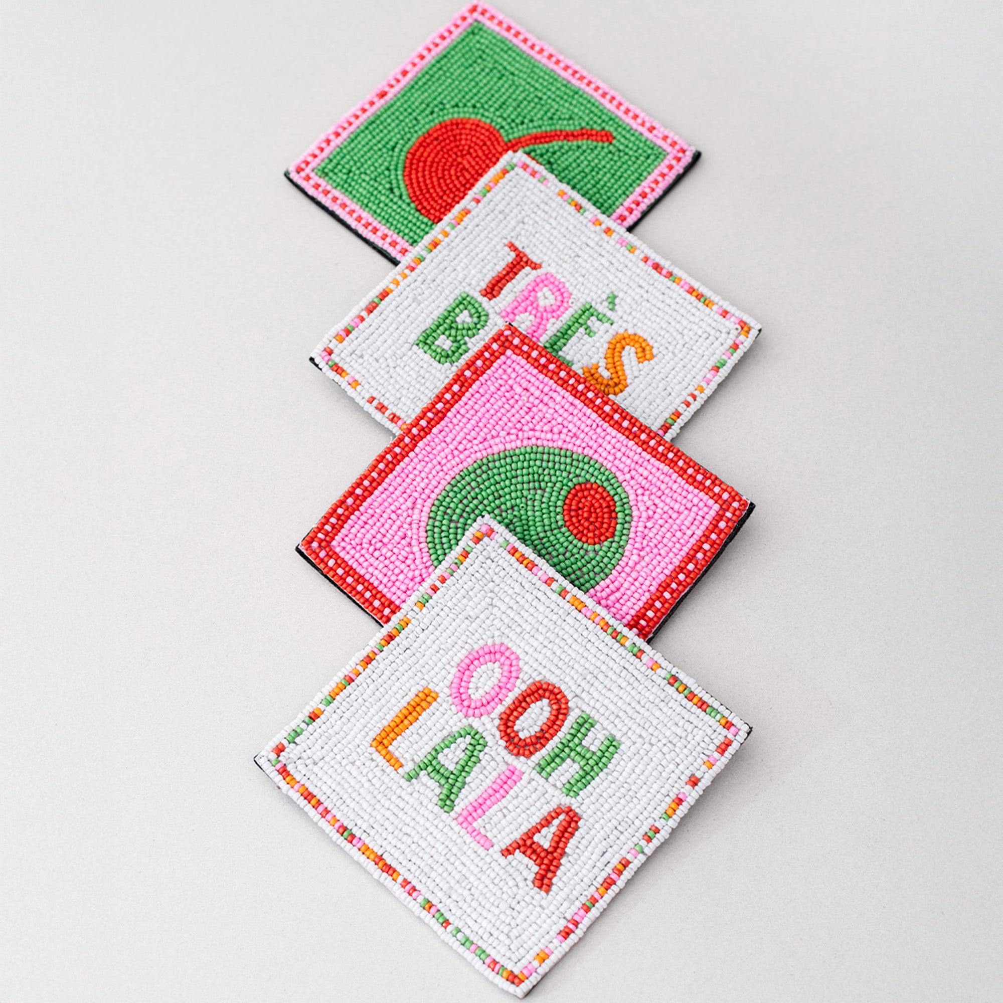 Four colorful coasters with text and designs on a light gray background