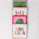 Colorful beaded pocket with 'Trés' and 'Ooh La La' text on a light gray background