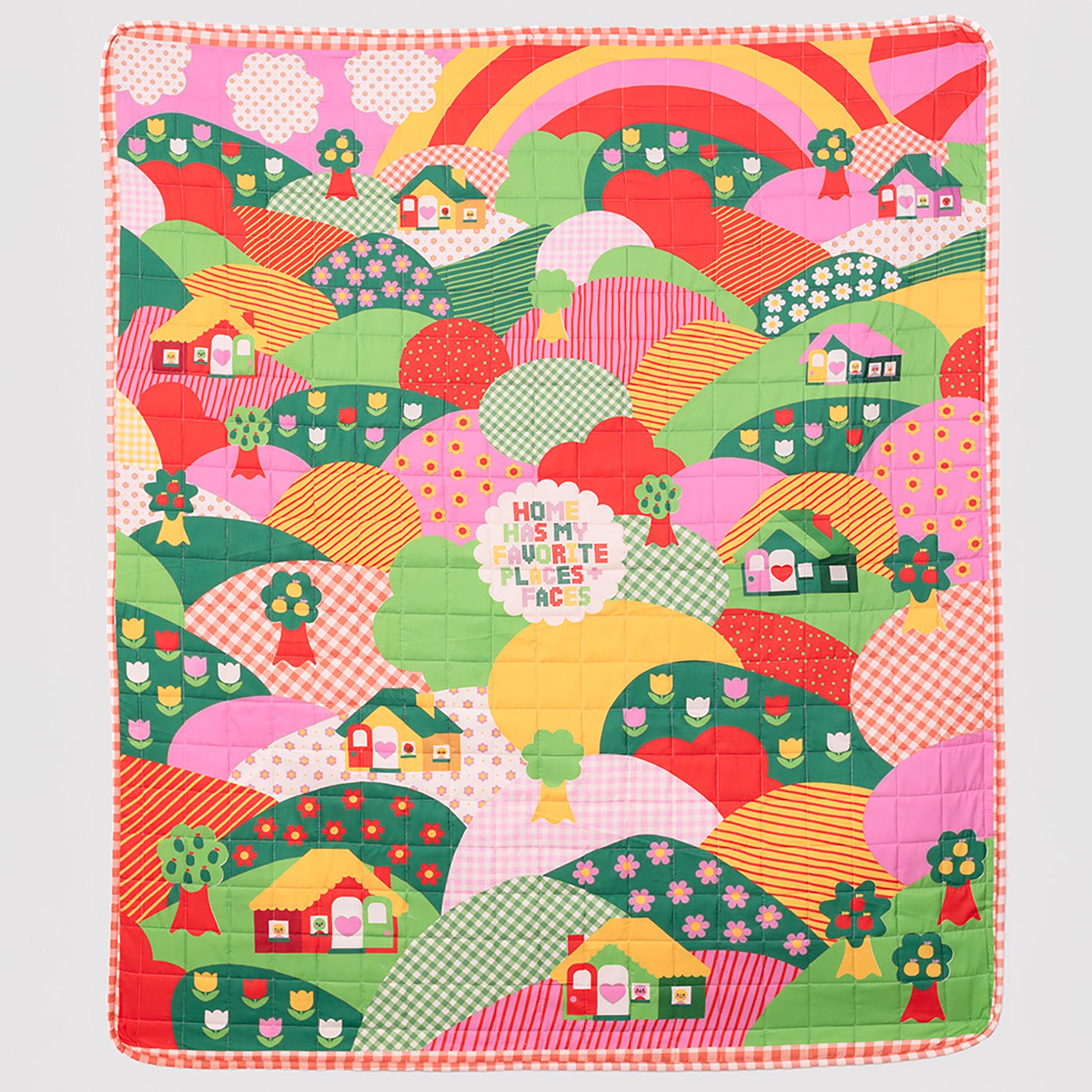 Colorful quilt with a pattern of houses, trees, and a rainbow on a white background