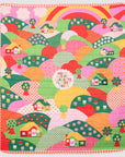 Colorful quilt with a pattern of houses, trees, and a rainbow on a white background