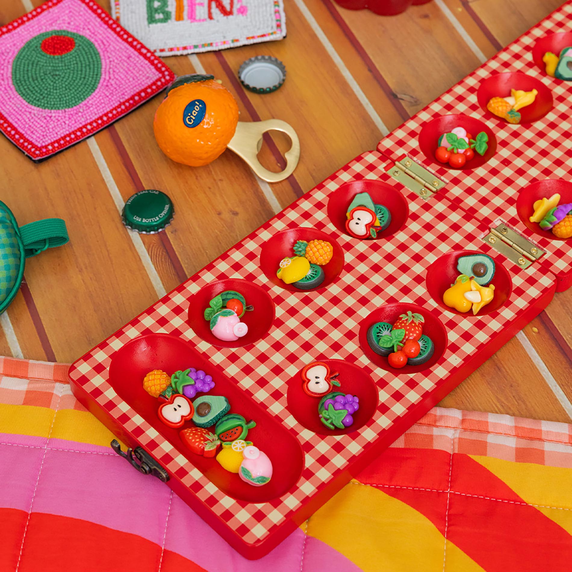 Red checkered mancala board with fruit-themed items on a light gray background