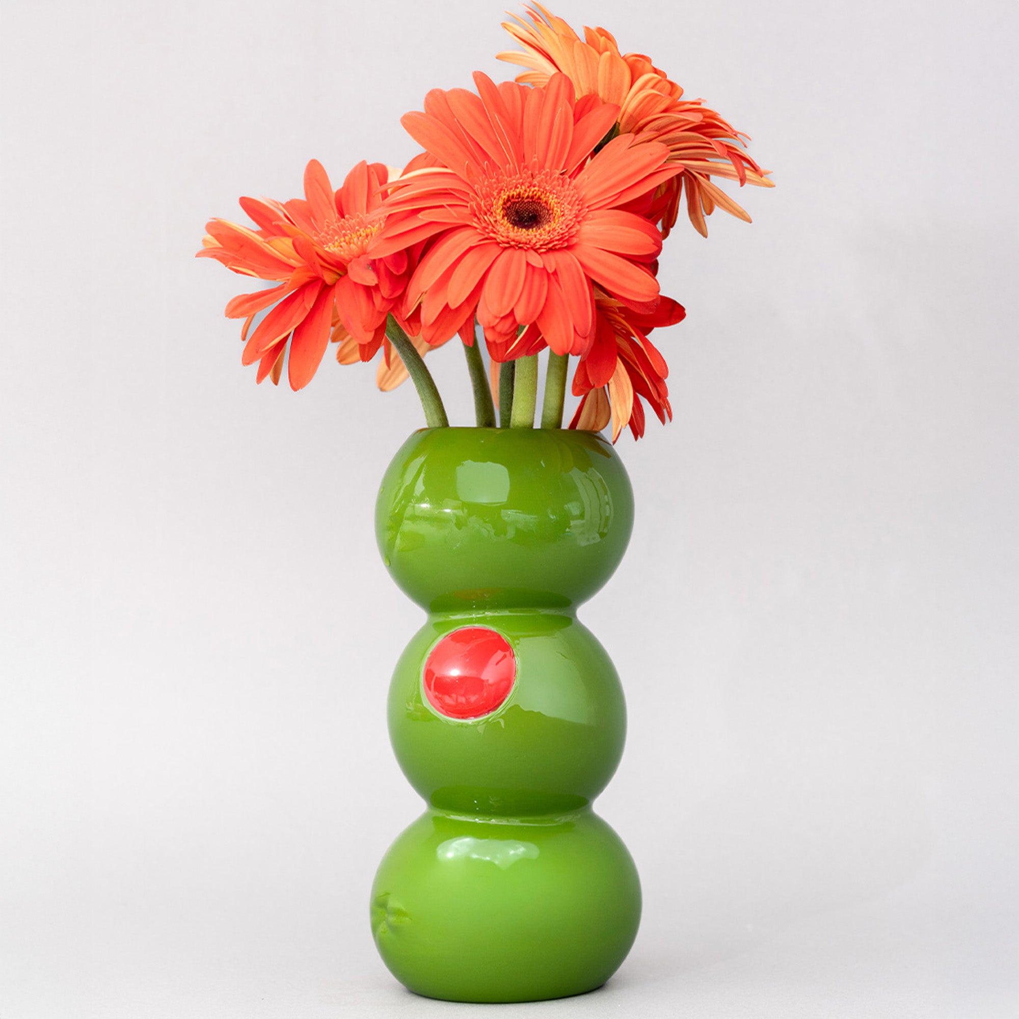 Green vase with orange flowers on a white background