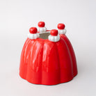 Red jello vase with white and red decorations on a light gray background