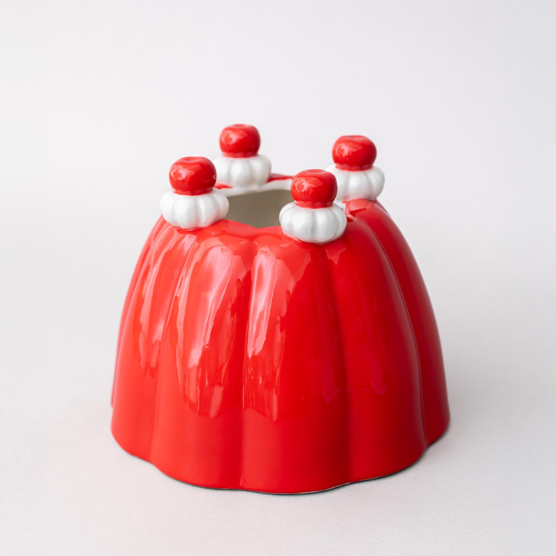 Red jello vase with white and red decorations on a light gray background