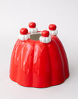 Red jello vase with white and red decorations on a light gray background