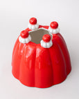 Red jelly mold vase with white and red decorative elements on a white background