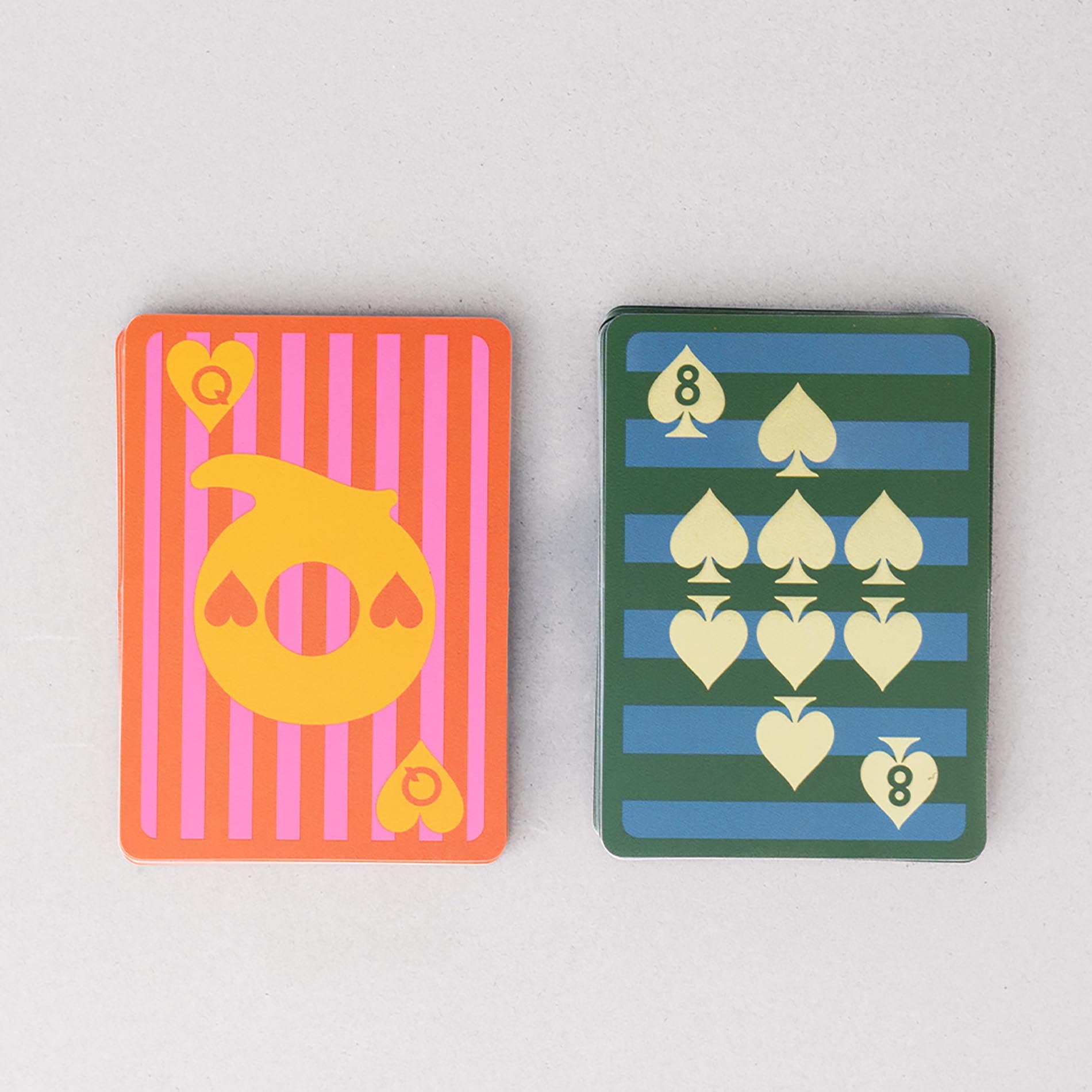 Two playing cards with colorful designs on a light gray background