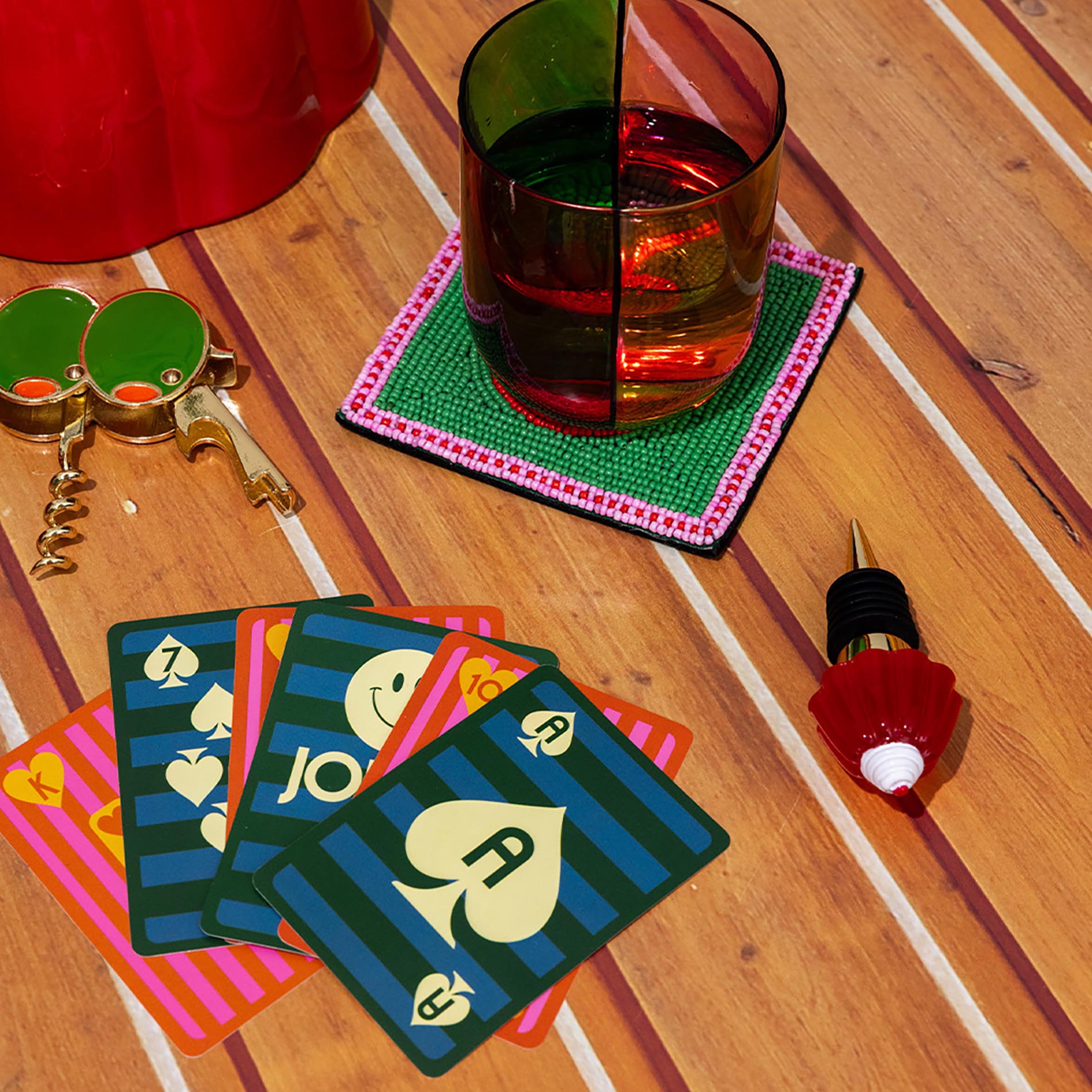 Playing cards, glass of red wine, and corkscrew on a wooden table.