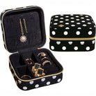 Black jewelry case with white polka dots containing gold jewelry, next to a matching black and white polka dot case.