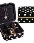 Black jewelry case with white polka dots containing gold jewelry, next to a matching black and white polka dot case.