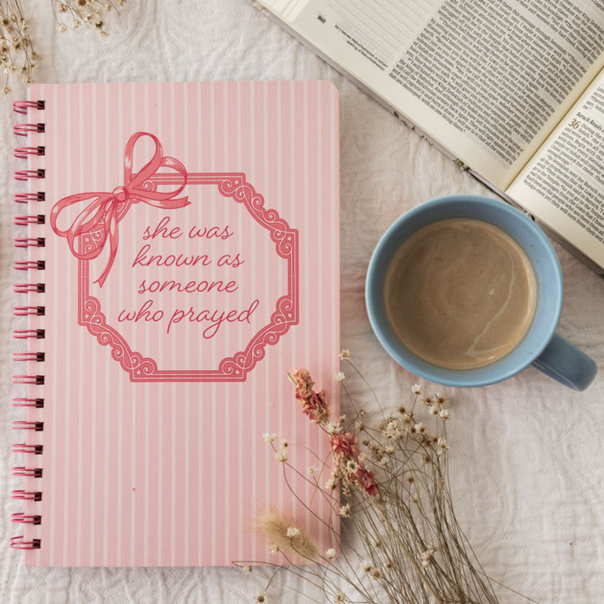 Pink notebook with decorative bow and text on a white background