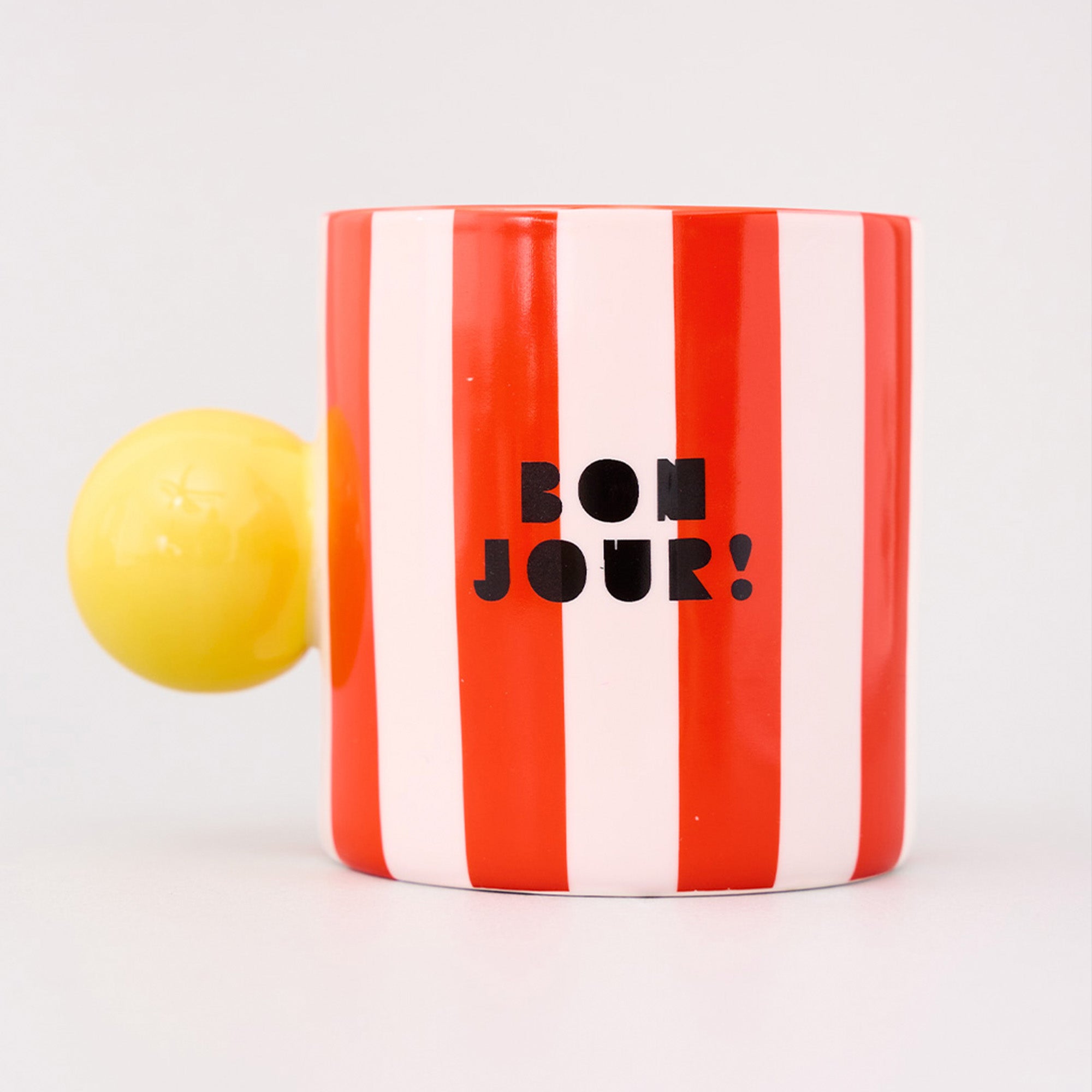 red and white vertical stripe mug with yellow ball handle and double sided typography with 'BONJOUR!' on one side and 'AU REVOIR' on the other