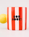red and white vertical stripe mug with yellow ball handle and double sided typography with 'BONJOUR!' on one side and 'AU REVOIR' on the other
