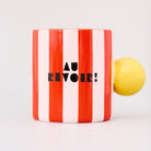 red and white vertical stripe mug with yellow ball handle and double sided typography with 'BONJOUR!' on one side and 'AU REVOIR' on the other