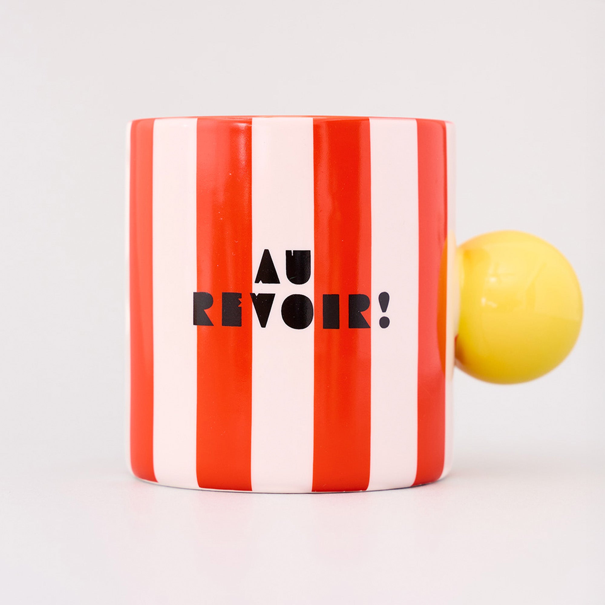 red and white vertical stripe mug with yellow ball handle and double sided typography with 'BONJOUR!' on one side and 'AU REVOIR' on the other