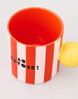 top view of red and white vertical stripe mug with yellow ball handle and double sided typography with 'BONJOUR!' on one side and 'AU REVOIR' on the other