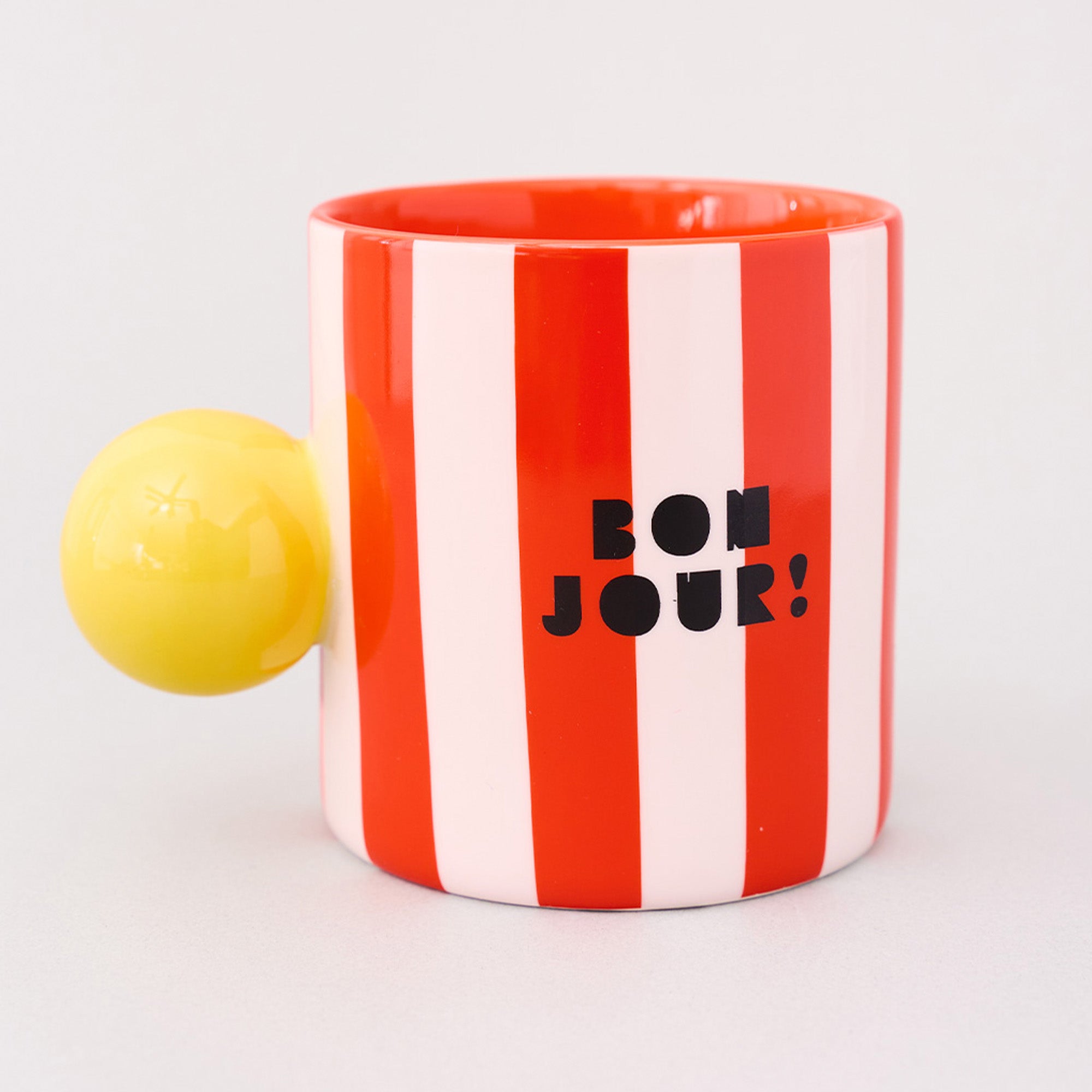 red and white vertical stripe mug with yellow ball handle and double sided typography with 'BONJOUR!' on one side and 'AU REVOIR' on the other