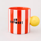 red and white vertical stripe mug with yellow ball handle and double sided typography with 'BONJOUR!' on one side and 'AU REVOIR' on the other