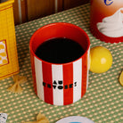 top view of red and white vertical stripe mug with yellow ball handle and double sided typography with 'BONJOUR!' on one side and 'AU REVOIR' on the other