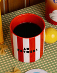 top view of red and white vertical stripe mug with yellow ball handle and double sided typography with 'BONJOUR!' on one side and 'AU REVOIR' on the other