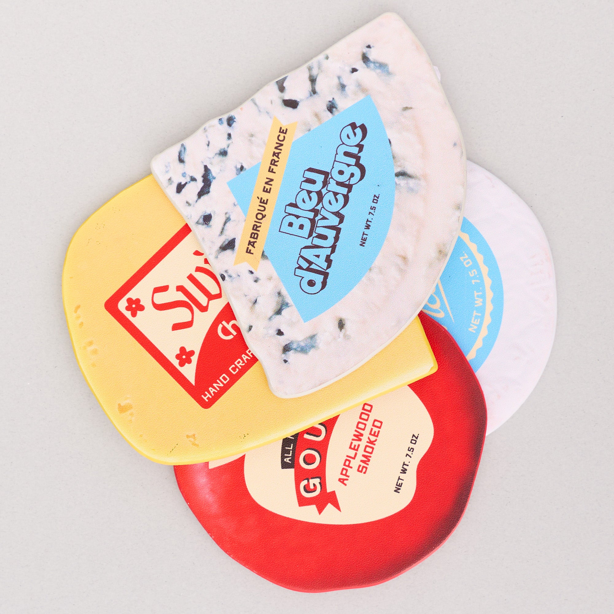 Side view of four different types of cheese coasters with labels on a light gray background