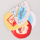 Side view of four different types of cheese coasters with labels on a light gray background