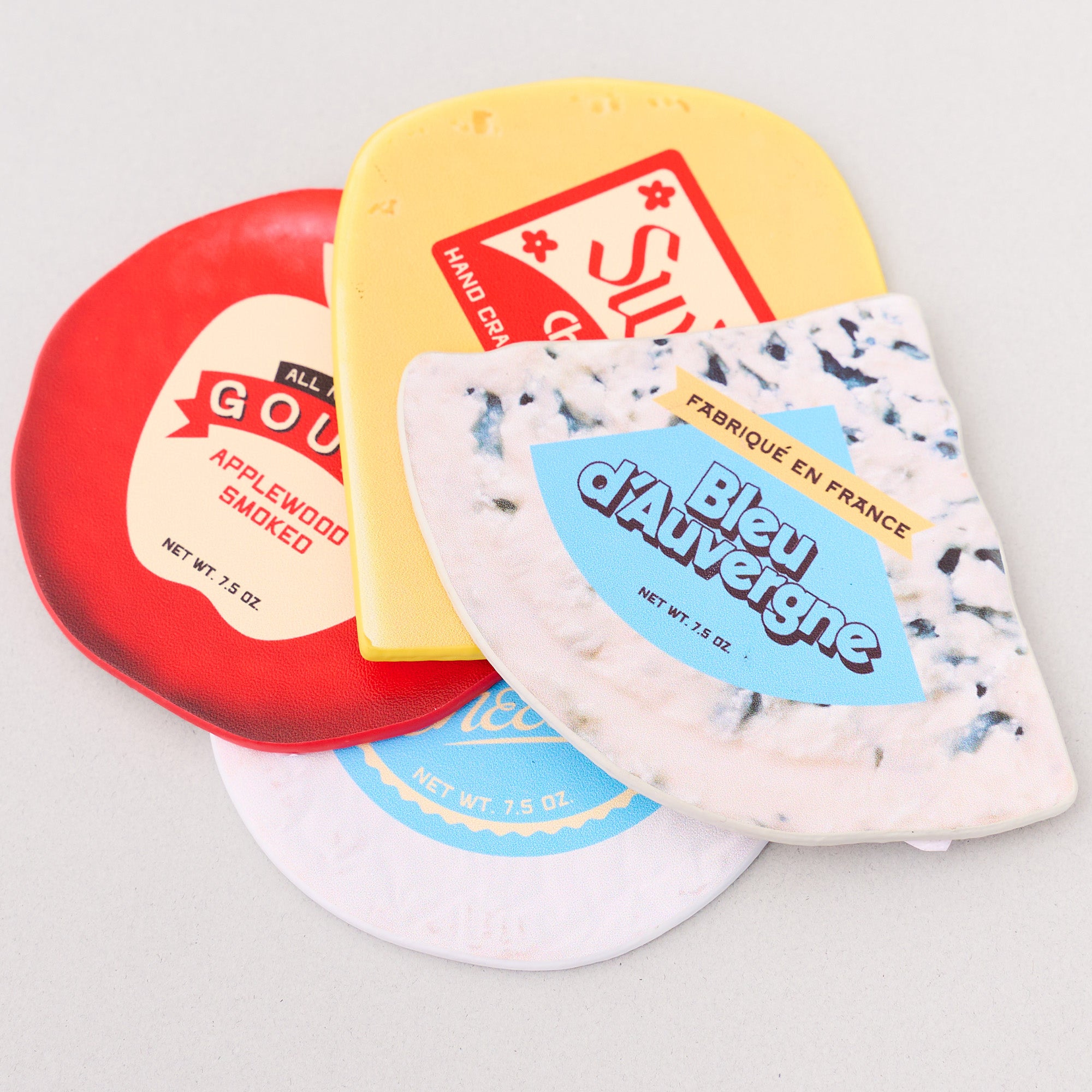 Four different types of cheese coasters with labels on a light gray background