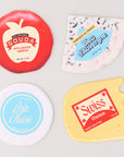 Flattened four different types of cheese coasters with labels on a light gray background