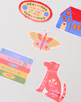 Set of colorful stickers including a butterfly, house, dog, and book-themed designs on a light gray background.