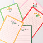 Set of lined notepads with floral designs on colorful borders.