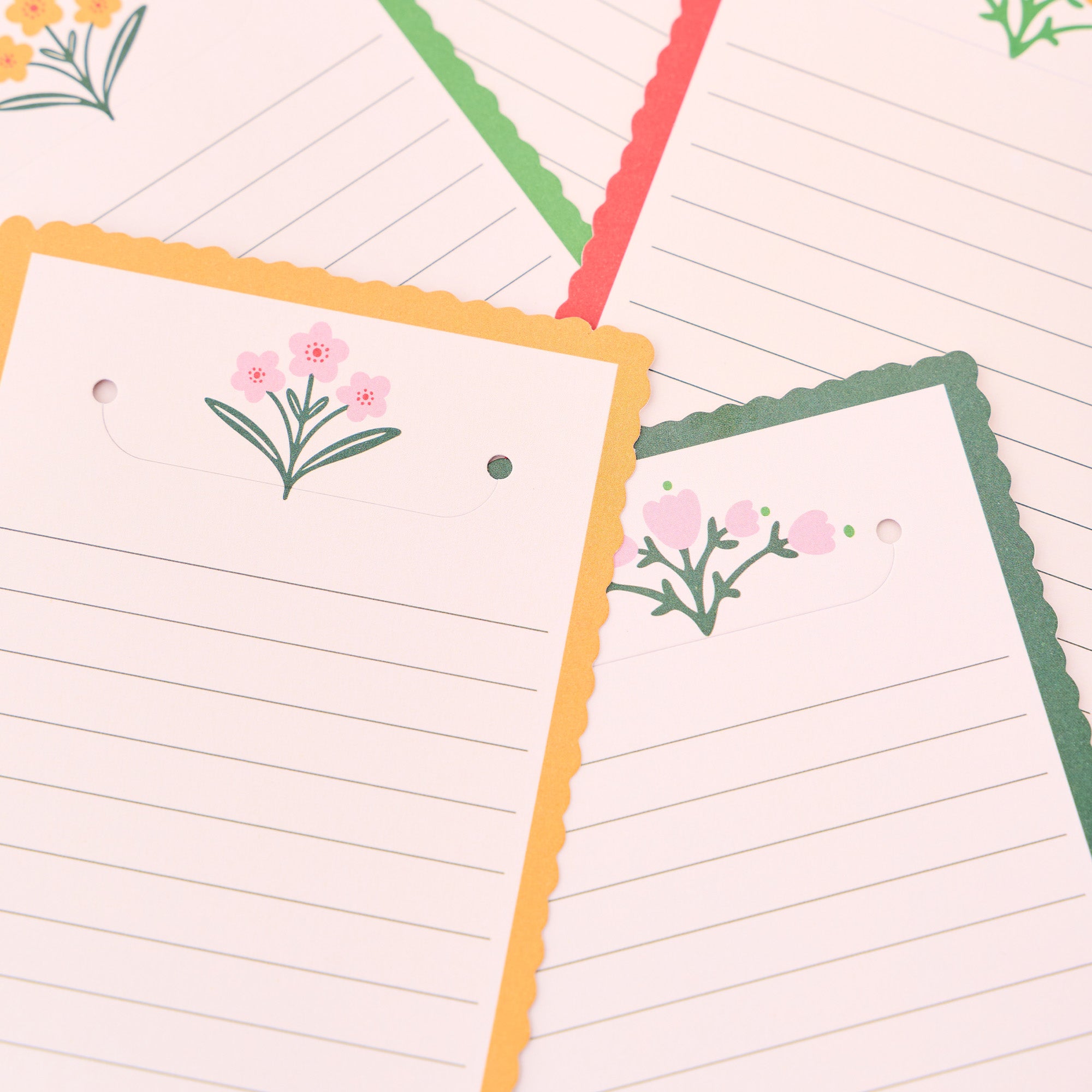 Two lined notepads with floral designs on a light pink background