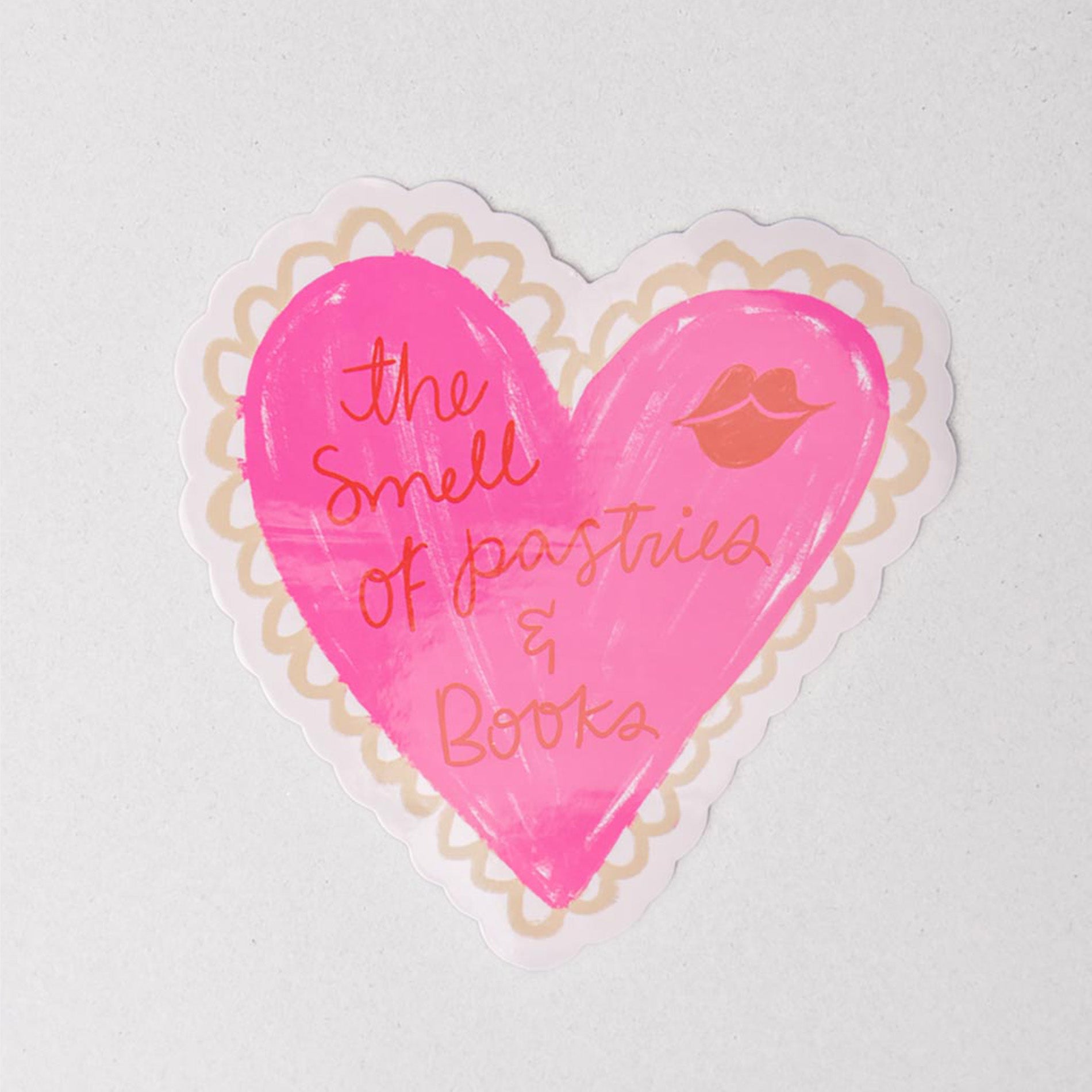 Pink heart-shaped sticker with text and a lip print on a white background