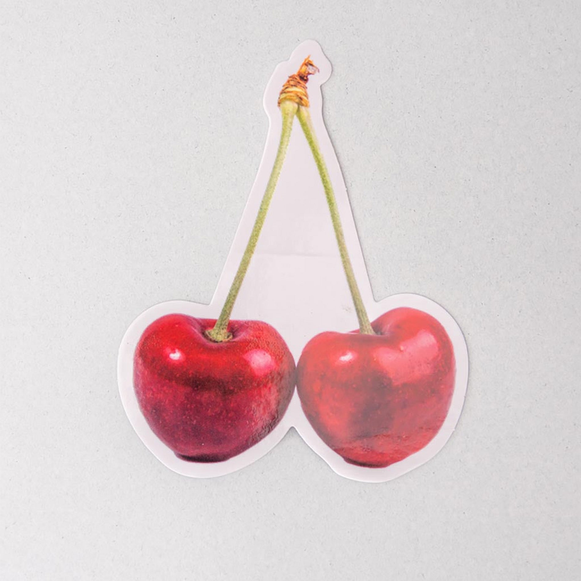 Sticker of two red cherries on a light gray background
