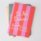 Notebook with 'Do Not Disturb! I'm Currently Lost In A Fantasy World And I Don't Want To Leave!' text on a gray background